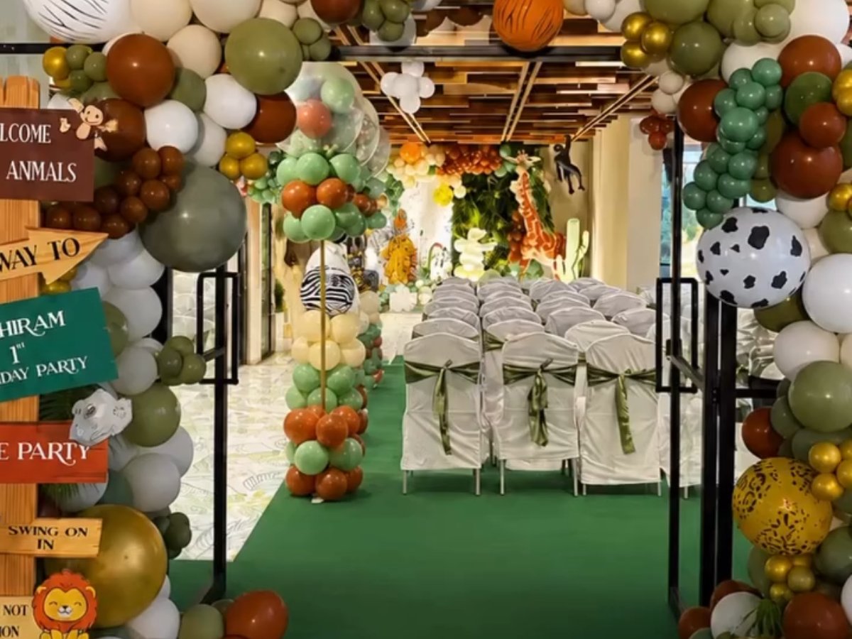 Jungle safari birthday setup with balloon arches, animal cutouts and a green aisle